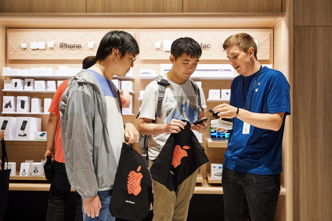 An Apple Battersea team member shows customers how to set up their new iPhone 14 purchases.